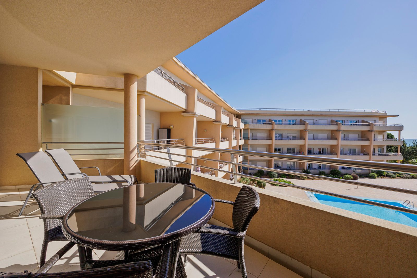 Balcony with dining table and sun loungers, looking across the pool