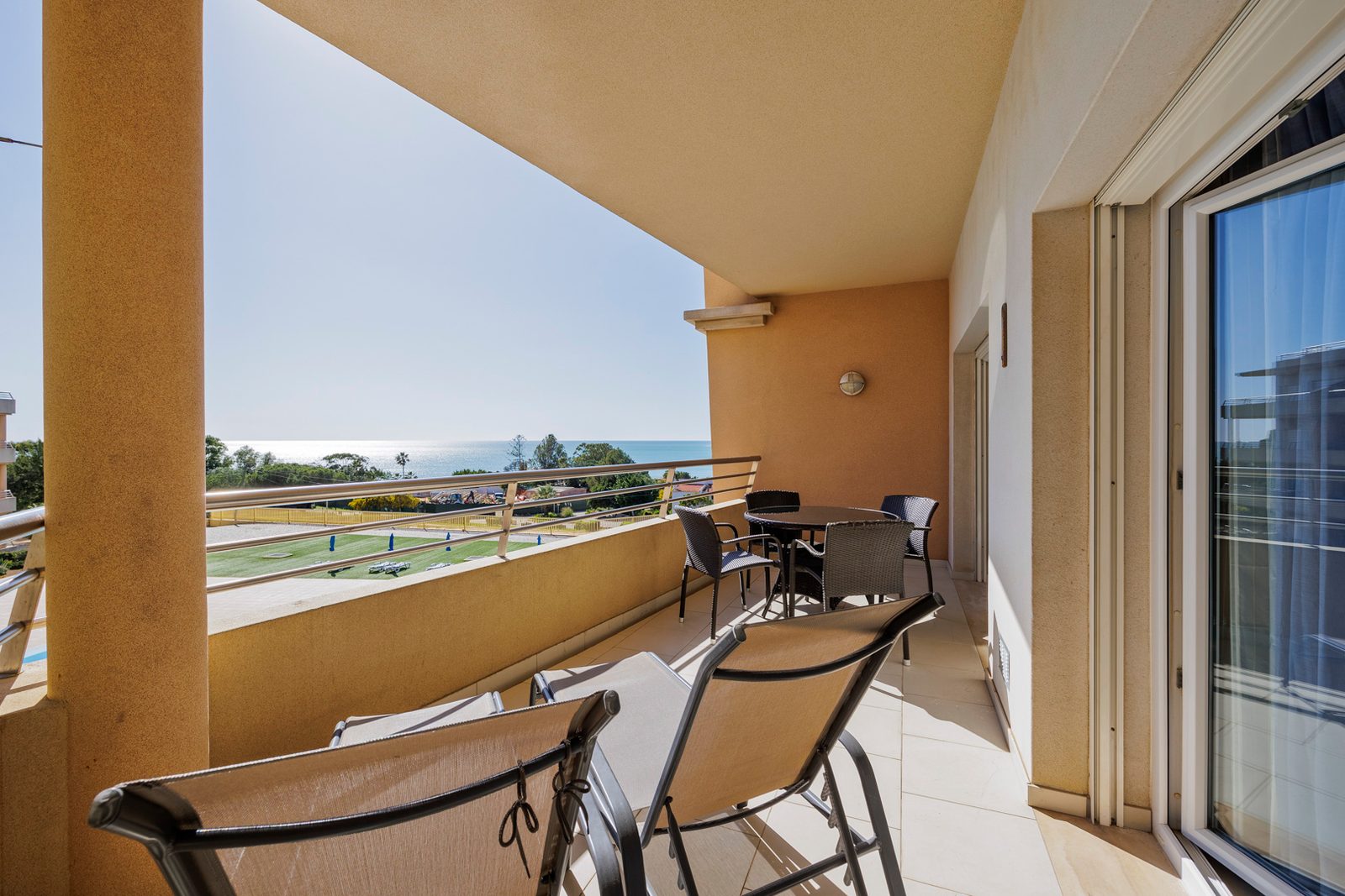 Balcony with sun loungers, dining table, and sea view