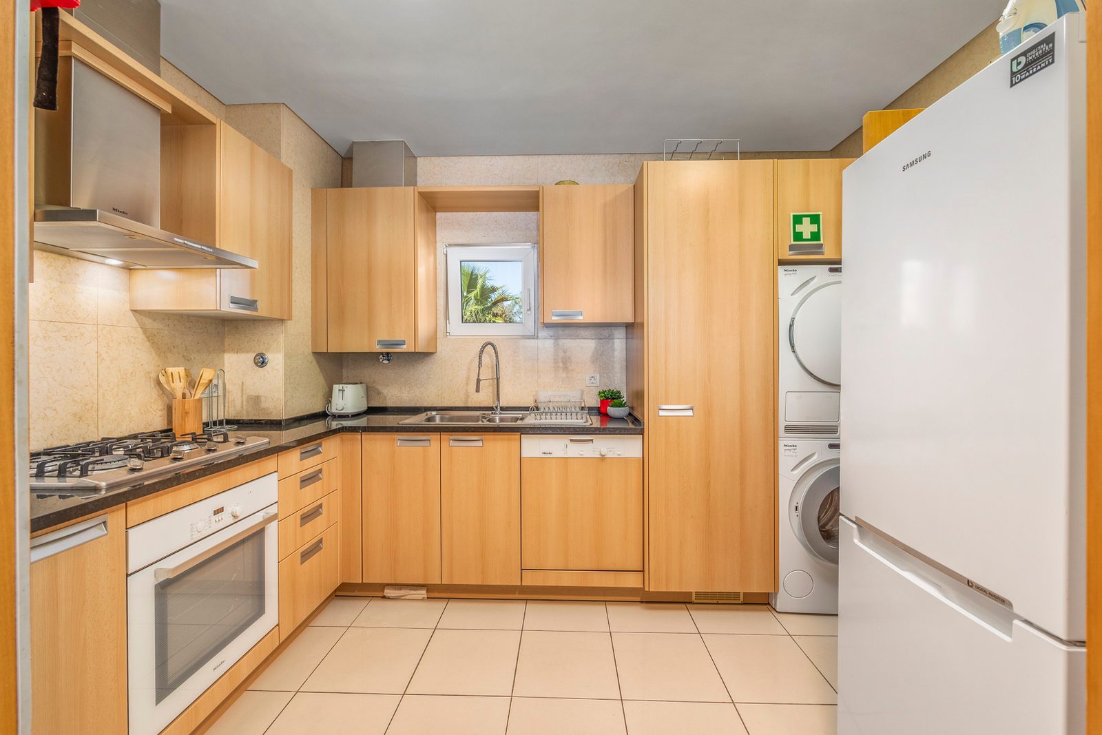 Kitchen with gas hob, oven, fridge-freezer, and stacked washer and dryer