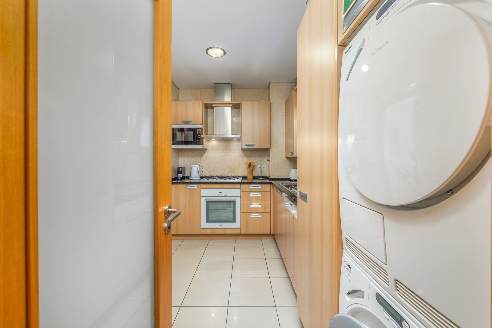 Kitchen seen from the hallway, with oven, microwave, and laundry appliances