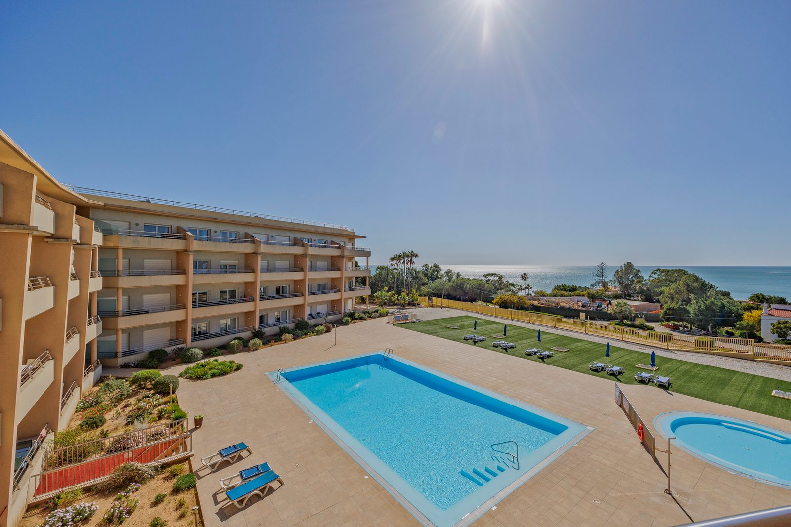 View from the balcony over the pool, sun lawn, and sea