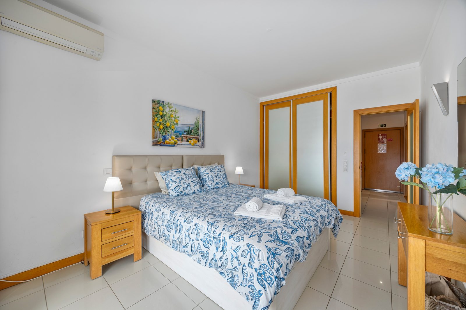 Bedroom with tan upholstered headboard and wall-mounted air conditioning