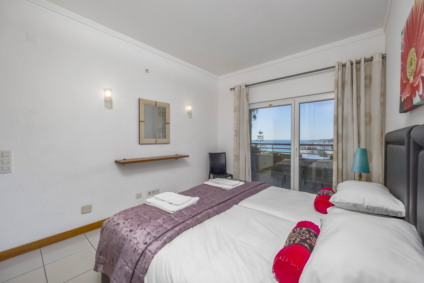 Bedroom with upholstered headboard and sea-view balcony access