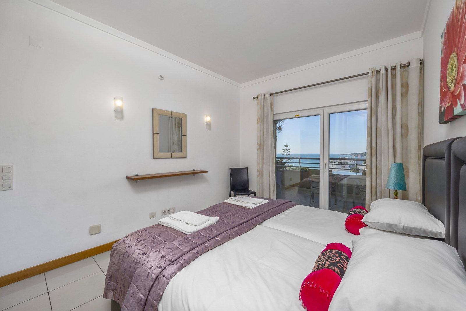Bedroom with upholstered headboard and sea-view balcony access