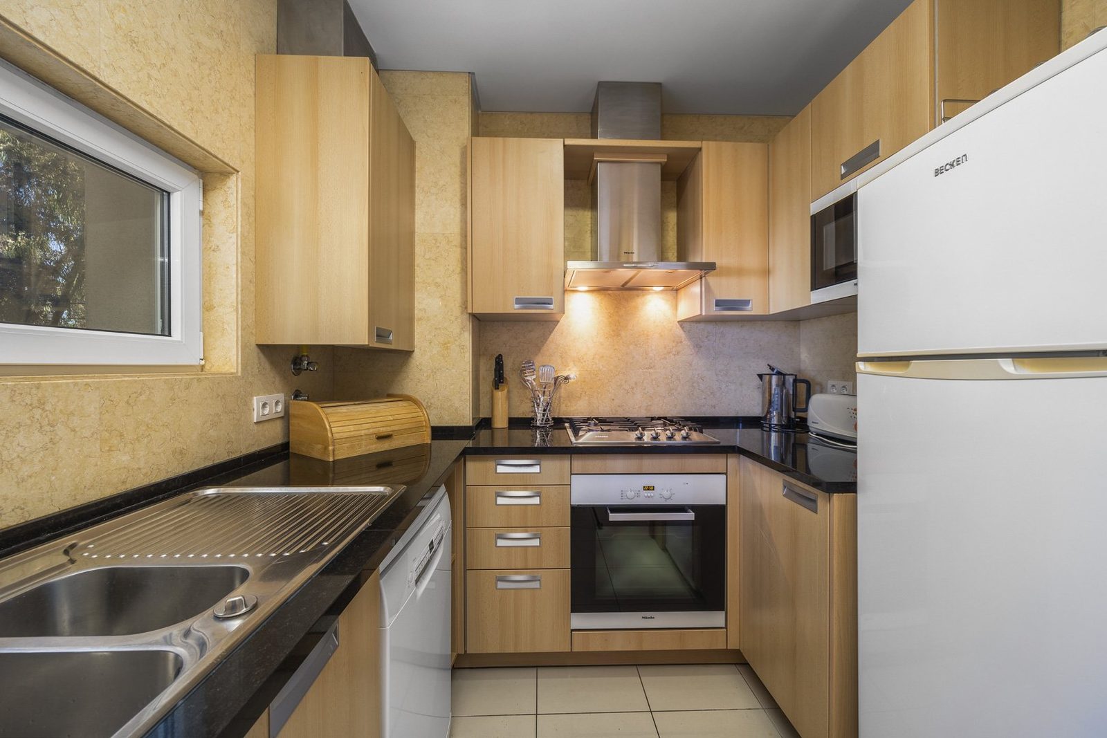 Kitchen with gas hob, extractor hood, and fridge-freezer