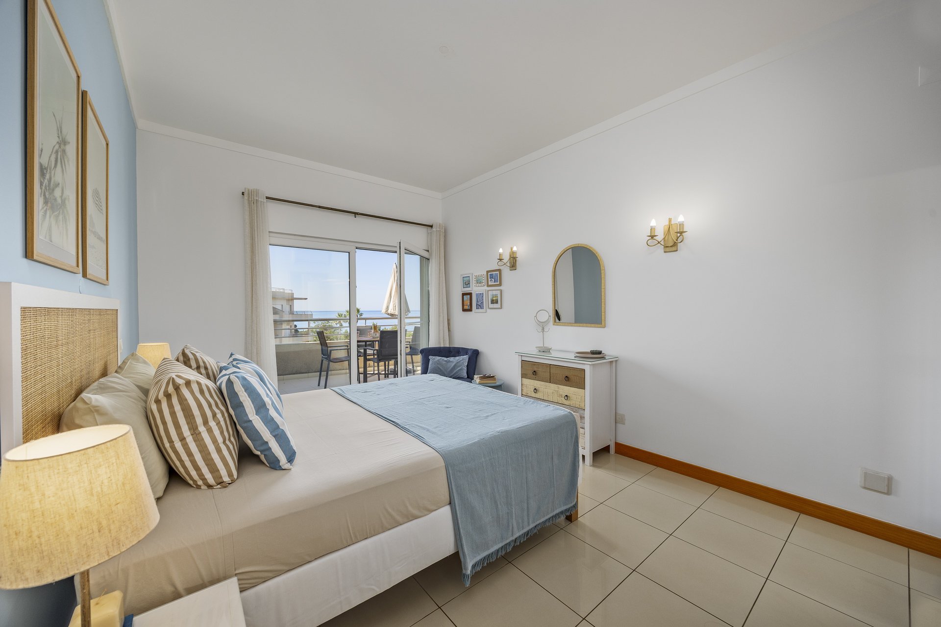 Bedroom with woven headboard, dresser, and sea-view balcony access