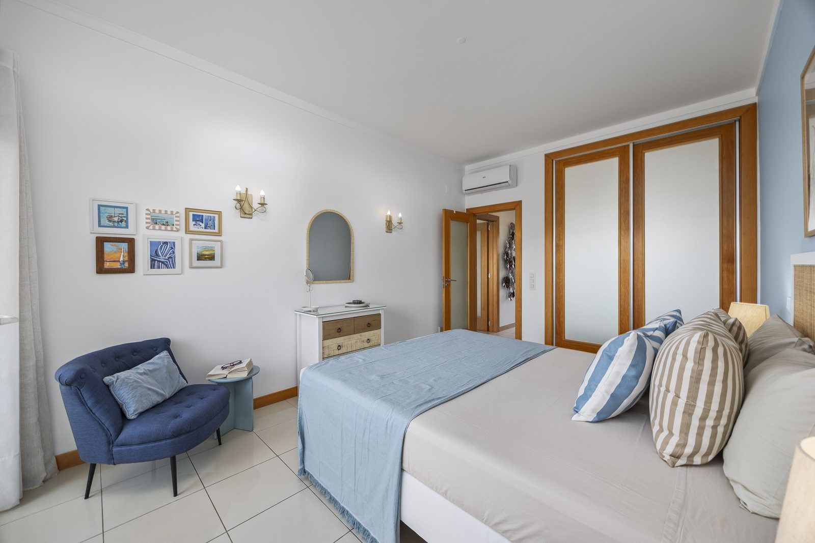 Bedroom with nautical artwork and blue armchair