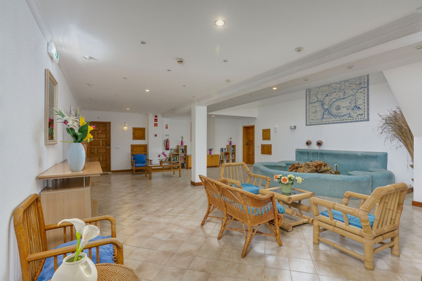 Communal lounge seating area with a decorative fountain and azulejo tile map