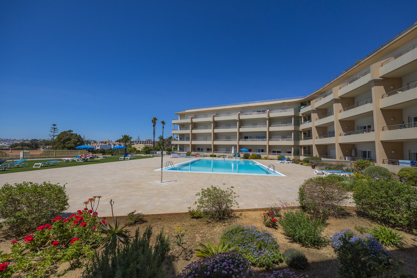 Wide view of the communal pool, sun loungers, and gardens