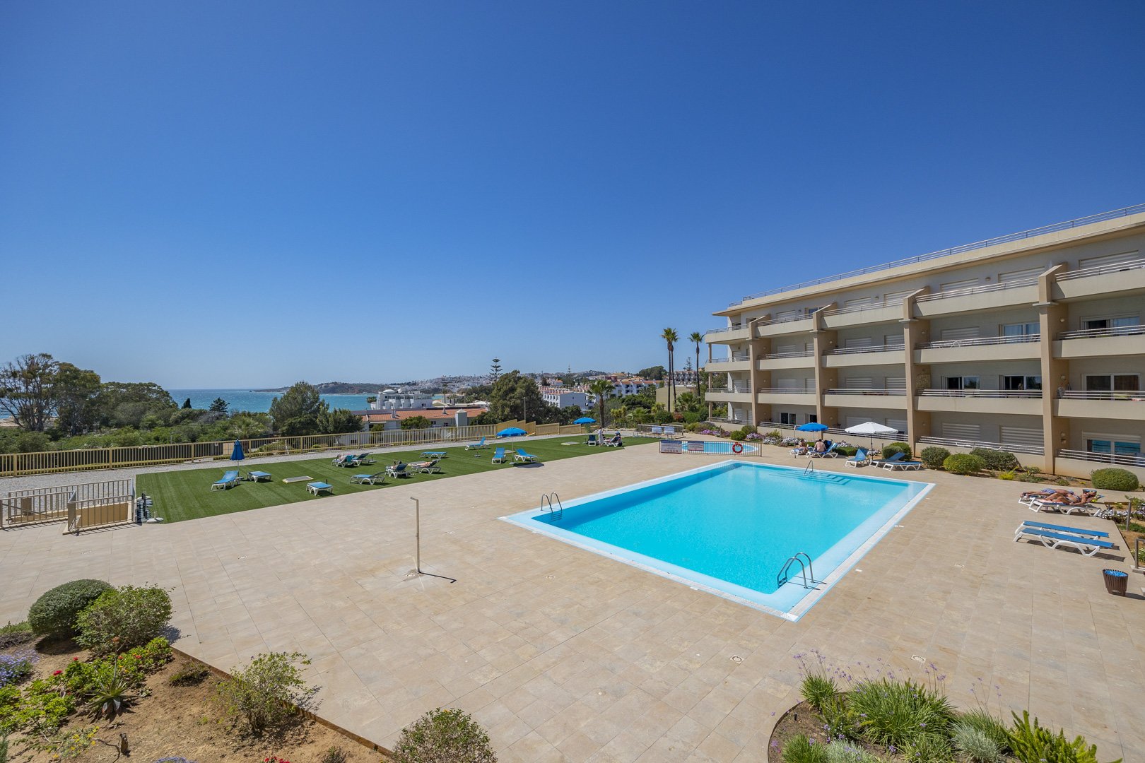 Wide view of the communal pool, sun lawn, and building