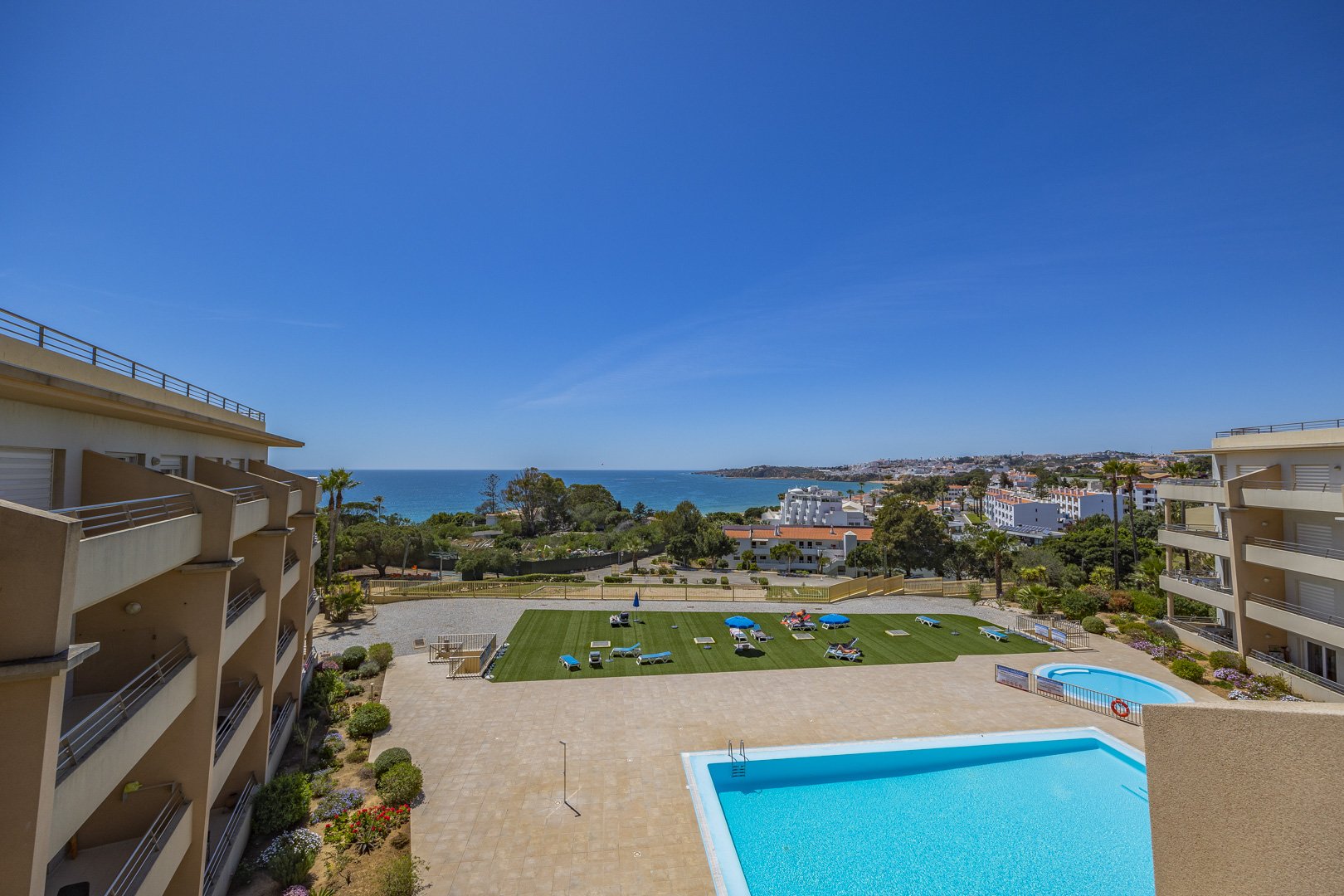 Elevated view of the communal pool, sun lawn, and the town beyond