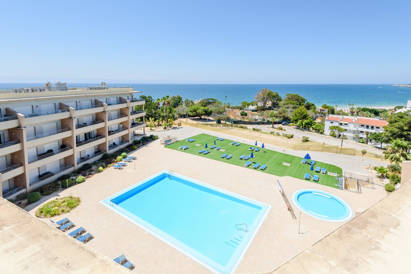 Elevated panoramic view of the pool, sun lawn, and sea