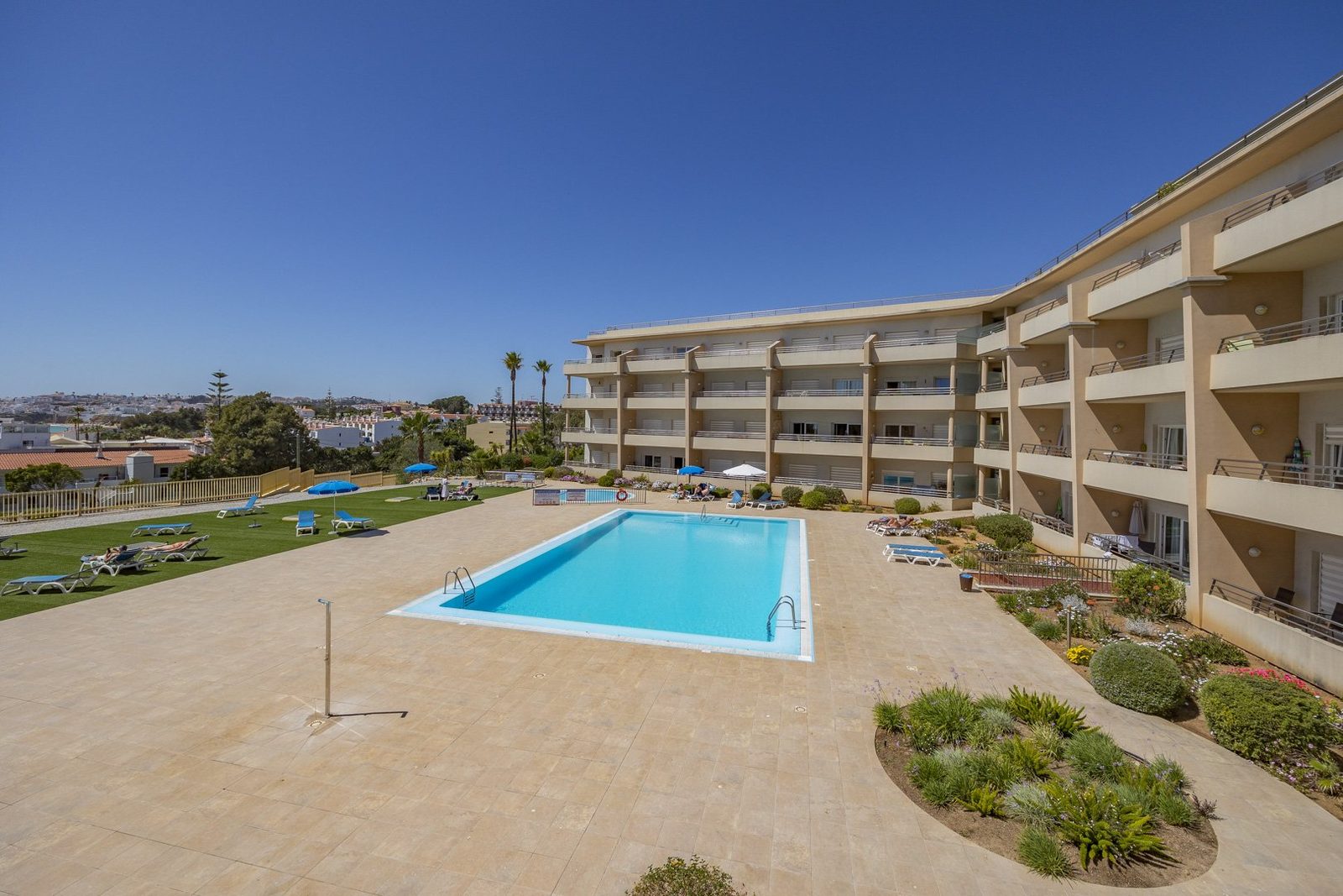 Wide view of the communal pool with the building and gardens