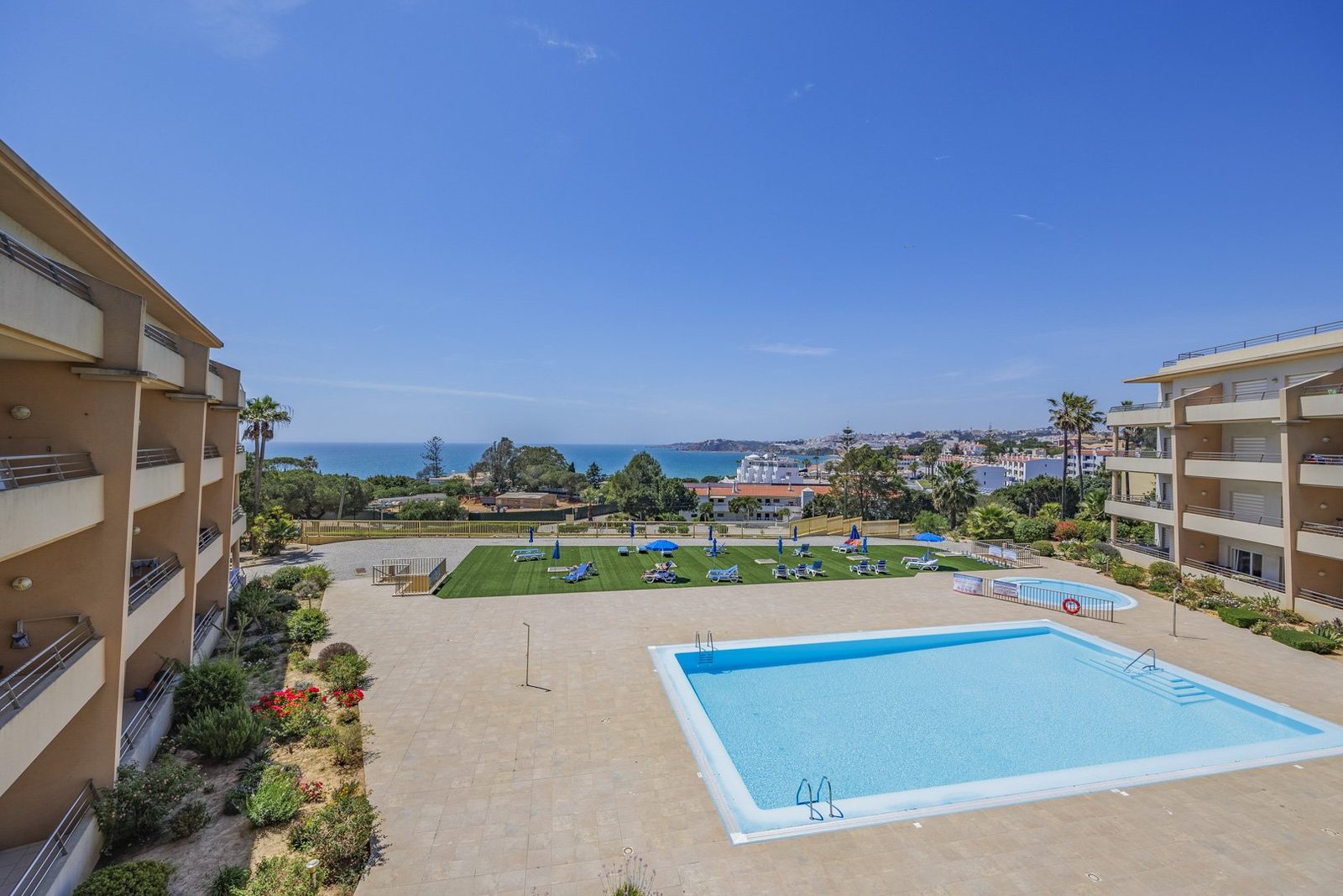 Elevated view over the pool, sun lawn, and sea from a balcony