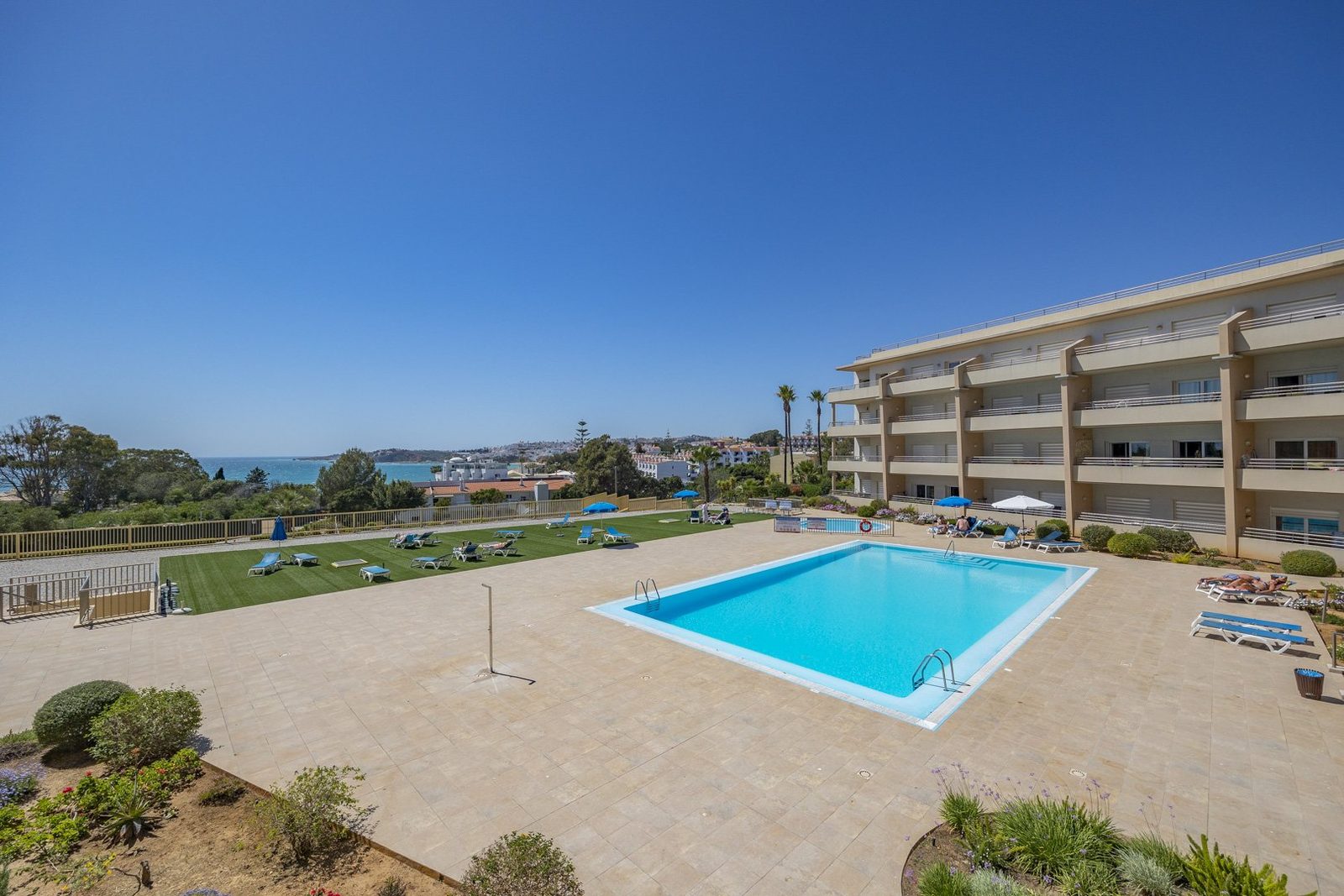 Wide view of the communal pool, sun lawn, and building