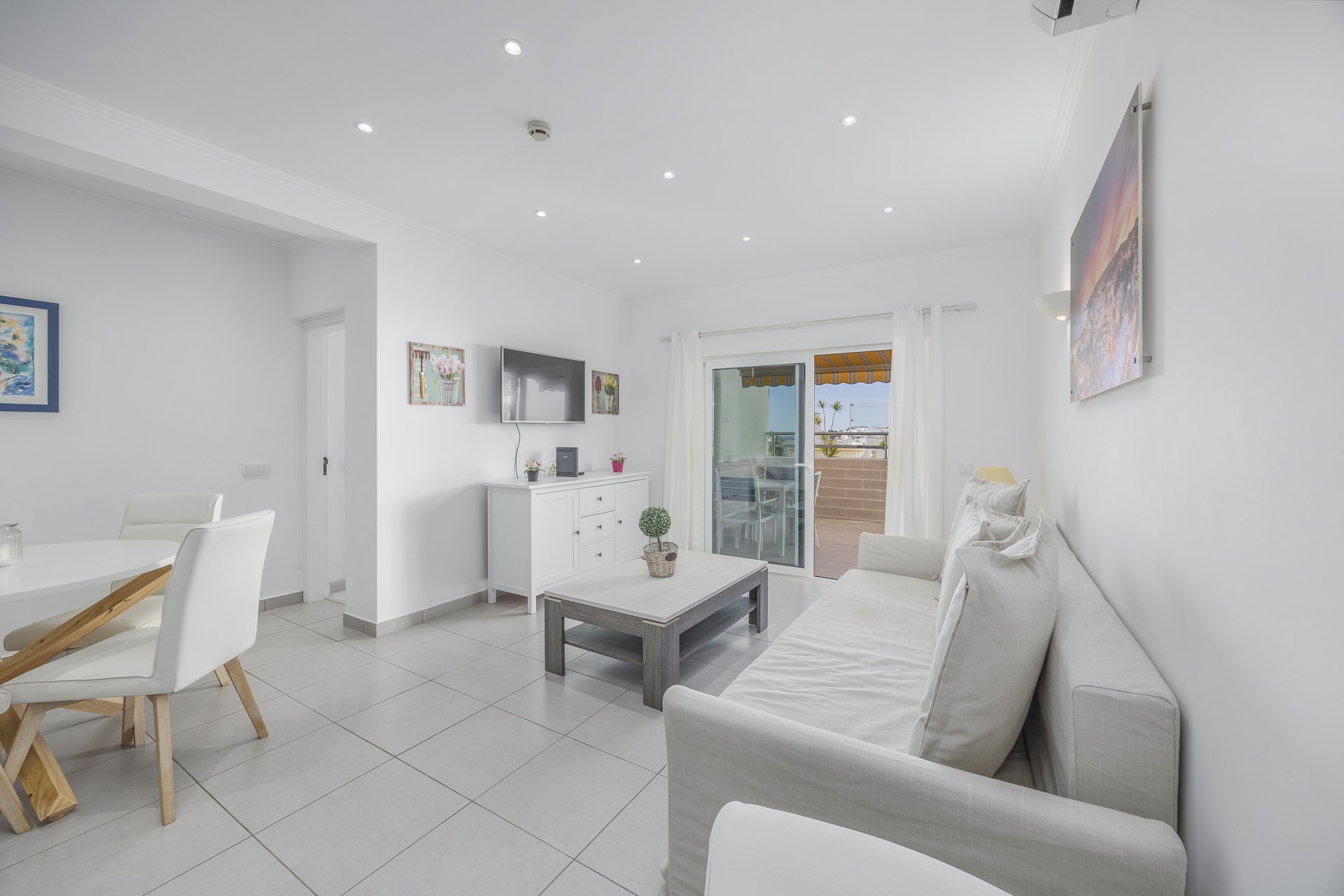 Living room with TV, sideboard, and balcony access