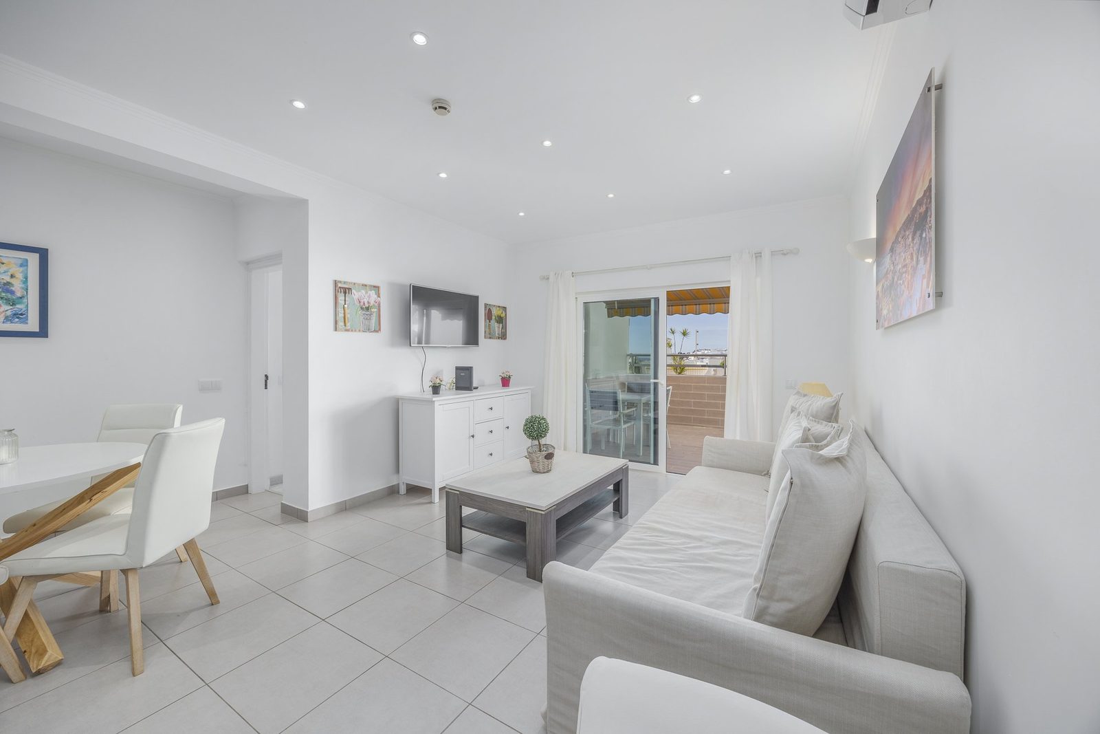 Living room with TV, sideboard, and balcony access