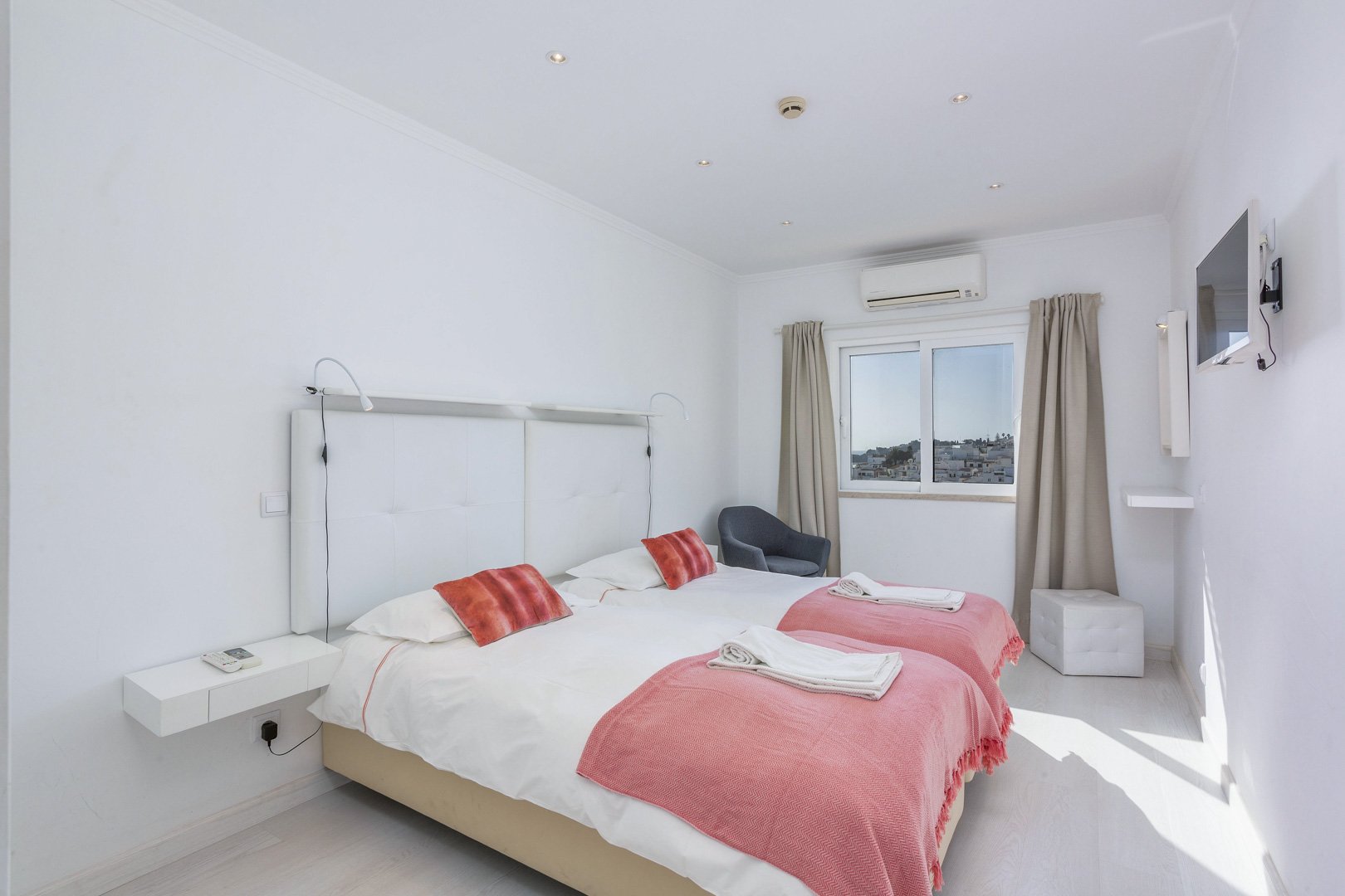 Twin bedroom with pink bedspreads and town view