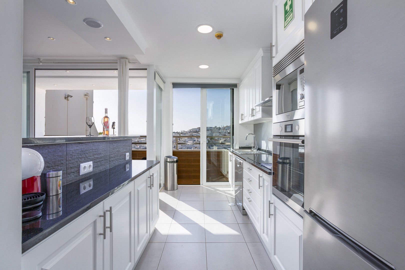 Galley kitchen with stainless steel appliances and balcony access