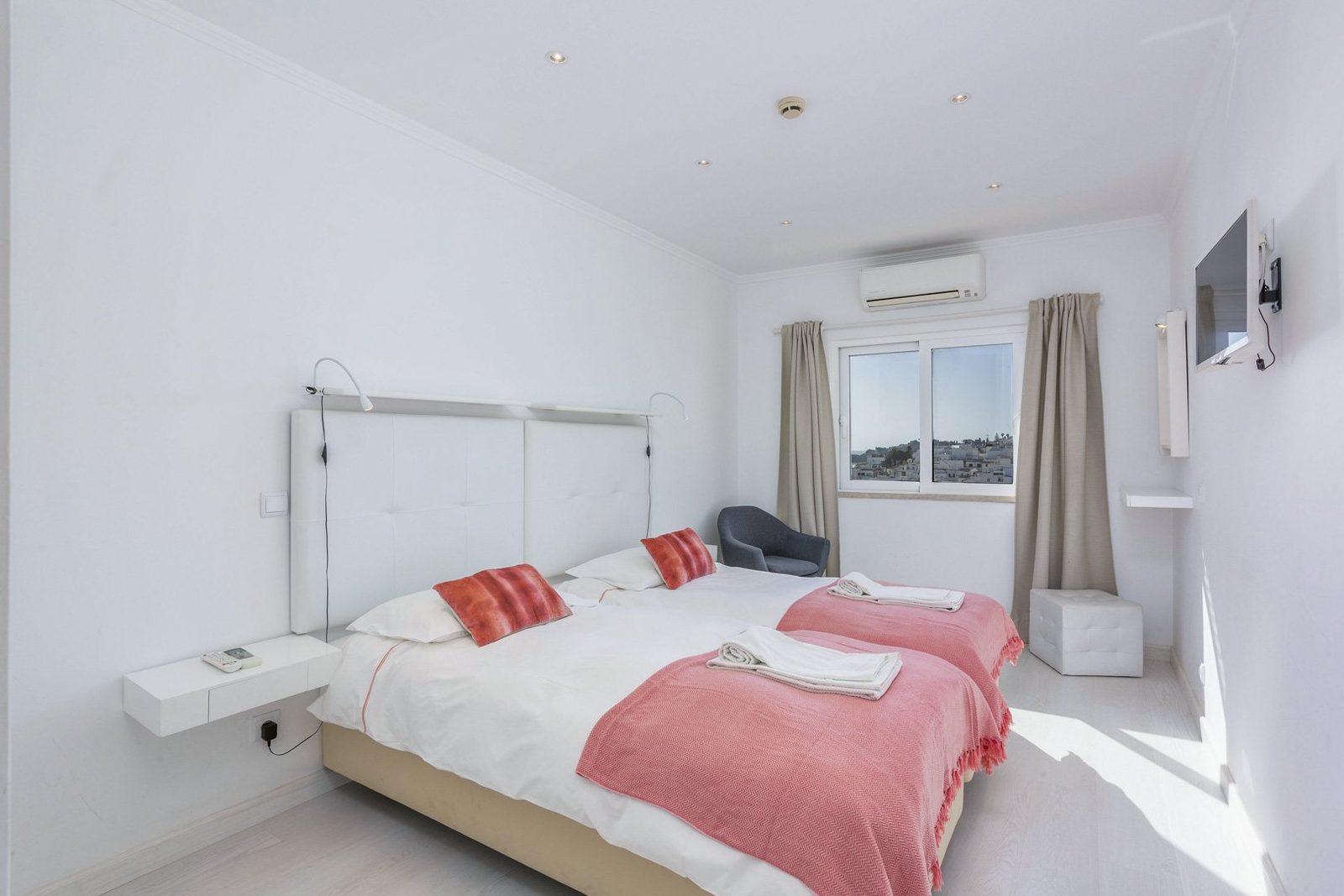Twin bedroom with pink bedspreads and town view