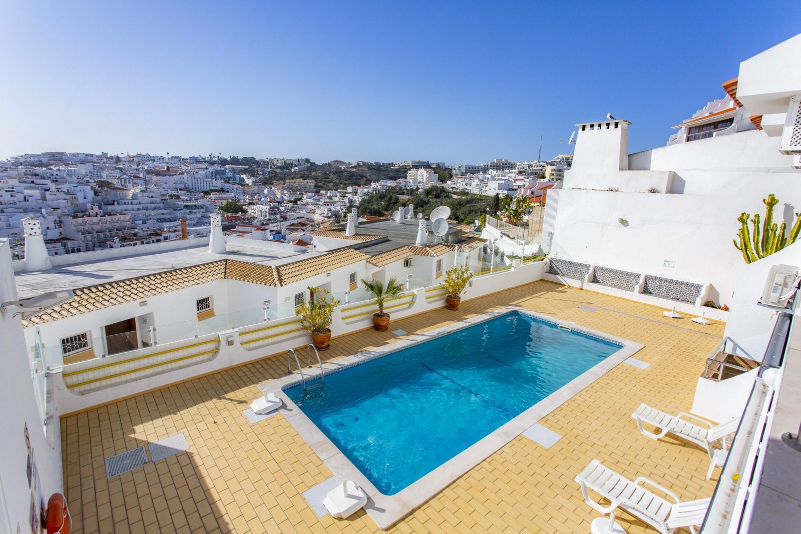 Private rooftop pool terrace with sun loungers and town view
