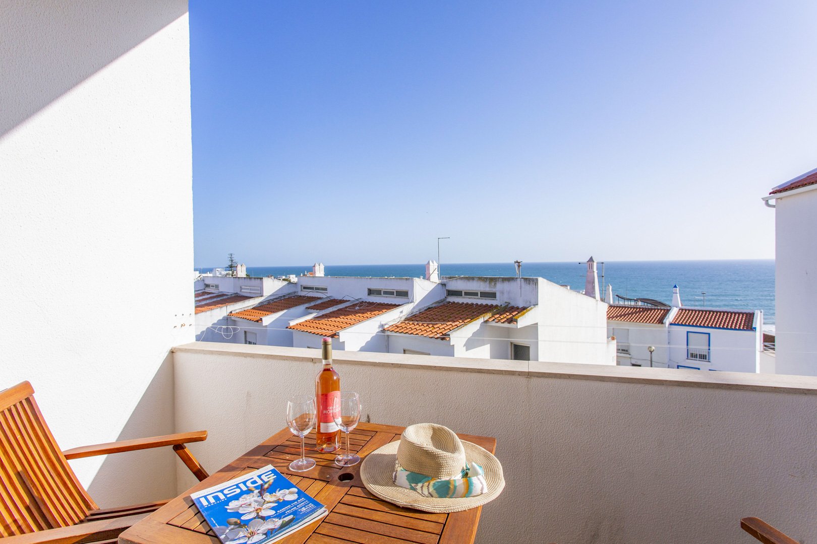 Balcony with bistro table, wine, and sea view