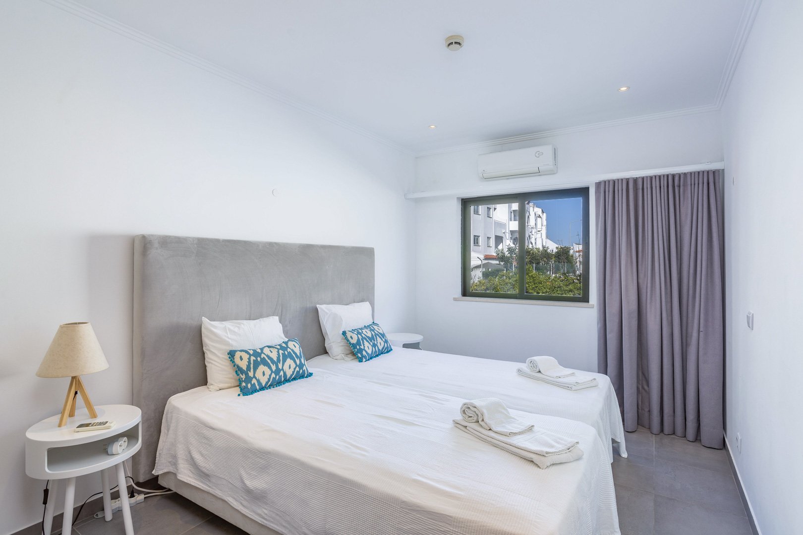 Twin bedroom with grey headboard and blackout curtains
