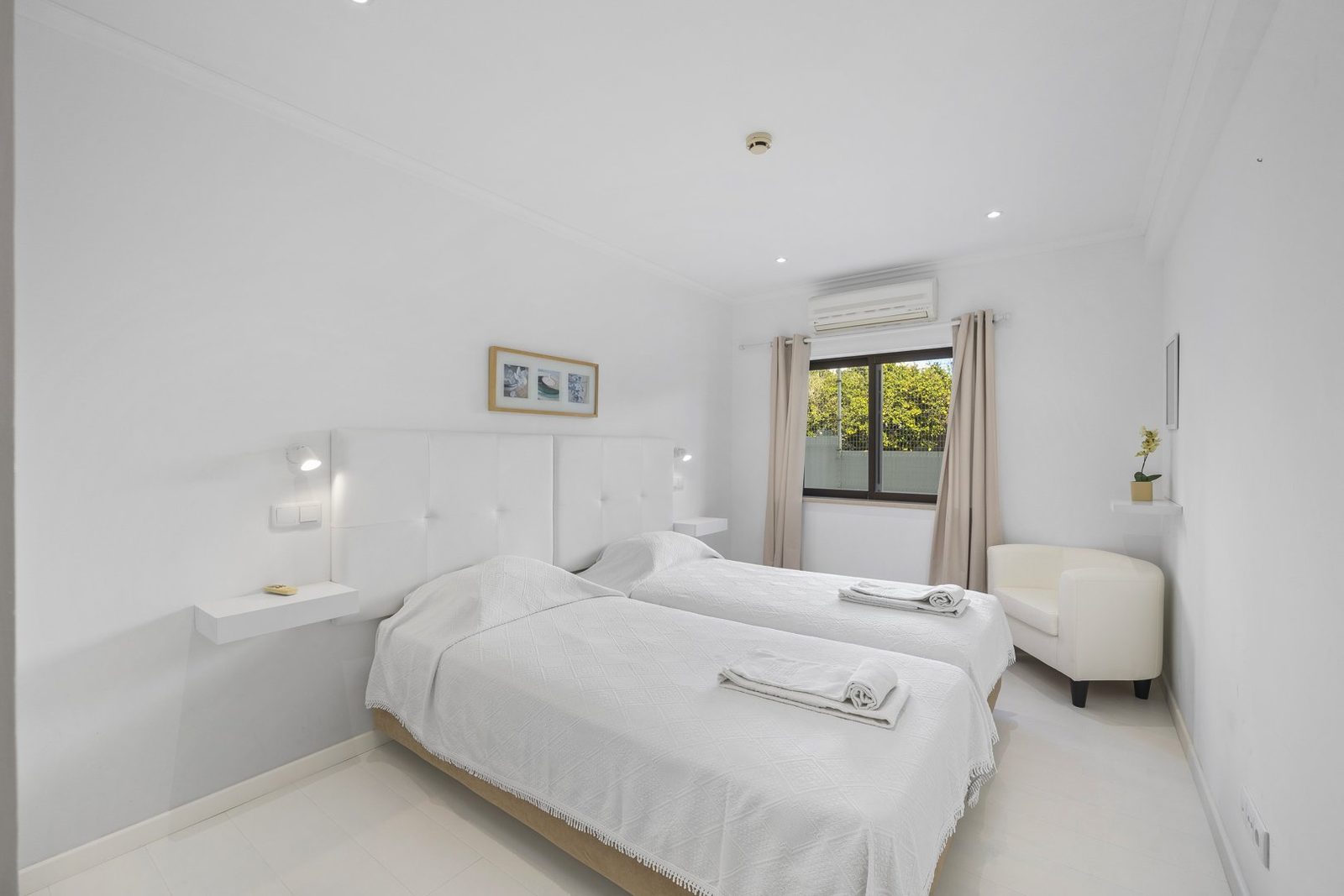 Twin bedroom with tufted headboard and armchair